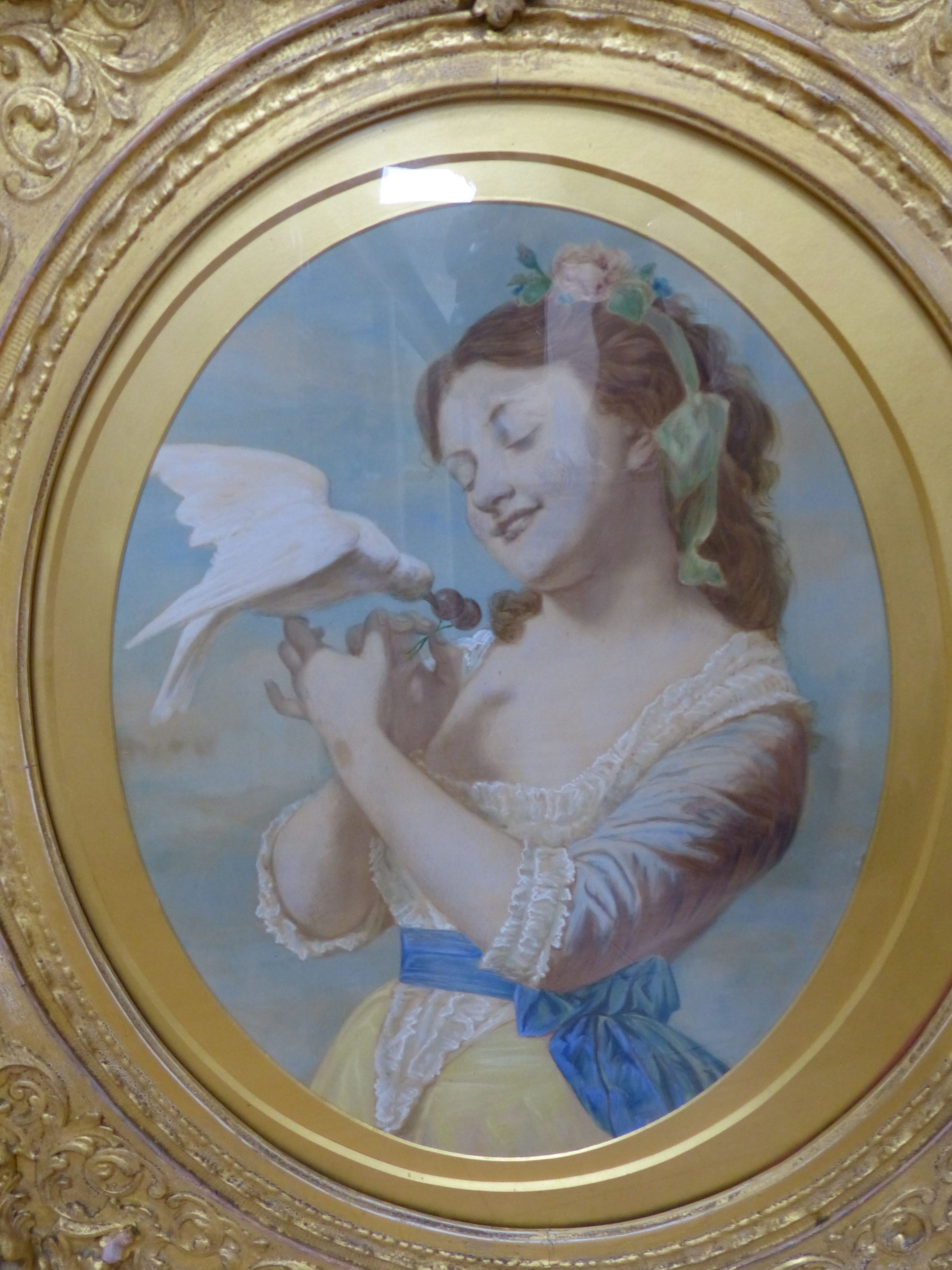 English School c.1900, overpainted print, Young woman with a dove, housed in a Victorian gilt gesso scroll frame, oval, 47 x 36cm, frame overall 76 x 66cm and a pastel portrait of a boy